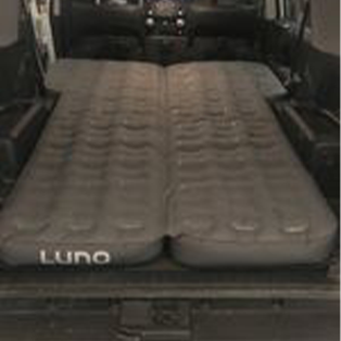 An inflated air mattress branded "Luno" is laid out in the back of an open van, covering the entire space from end to end.