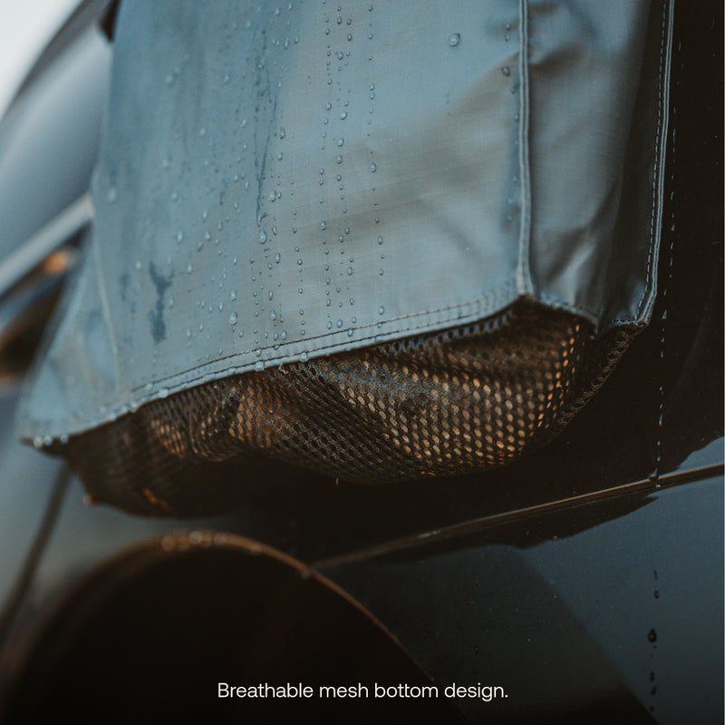 A close-up of the Luno® Gear & Shoe Storage Bag, featuring a water-resistant cover and breathable mesh bottom, shown attached to a car side with water droplets visible. Text reads: "Breathable mesh bottom design.