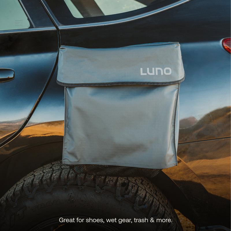 A gray Luno® Gear & Shoe Storage Bag is attached to the rear of a black vehicle above the tire. Text at the bottom reads: "Great for shoes, wet gear, trash & more.