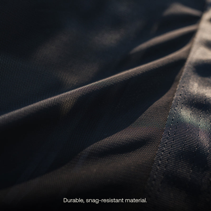 A close-up of the Sunroof Window Screen (Pre-Owned) by Luno HQ showcases its textured, dark fabric surface with a text overlay that reads "Durable, snag-resistant material." This design is crafted to provide excellent airflow while blocking insects, with the interplay of light and shadow creating subtle highlights.