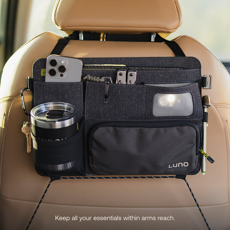 The pre-owned Luno HQ Seatback Organizer, attached to a tan car seat, neatly holds your smartphone, keys, flashlight, and stainless steel tumbler. Featuring multiple pockets and the Luno logo, it keeps essentials close. Available with USA shipping for added convenience.