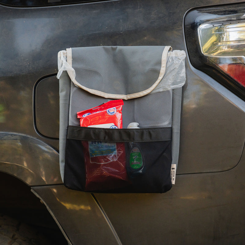 The Car Trash Can, crafted from upcycled materials in sleek gray and black, hangs conveniently in your car and comes stocked with sanitizing wipes, a pack of baking soda, a red pouch, and a small bottle of hand sanitizer—making it an essential addition to your camping accessories.