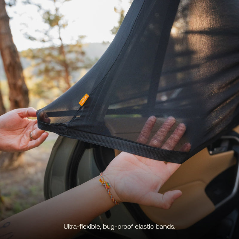 A person is showcasing the pre-owned Car Window Screens by Luno HQ near a car door, highlighting their ultra-flexible, black mesh material and bug-proof elastic bands amidst an outdoor background with trees. The screens appear to be in like-new condition, making them ideal for upgrading your existing gear.