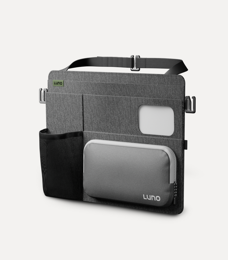 A gray and black travel organizer with multiple compartments is shown. The organizer features a main pocket with a zipper, a smaller front pocket, and an additional mesh pocket on the side. The brand name "Luno" is displayed on both the front pocket and a green tag.