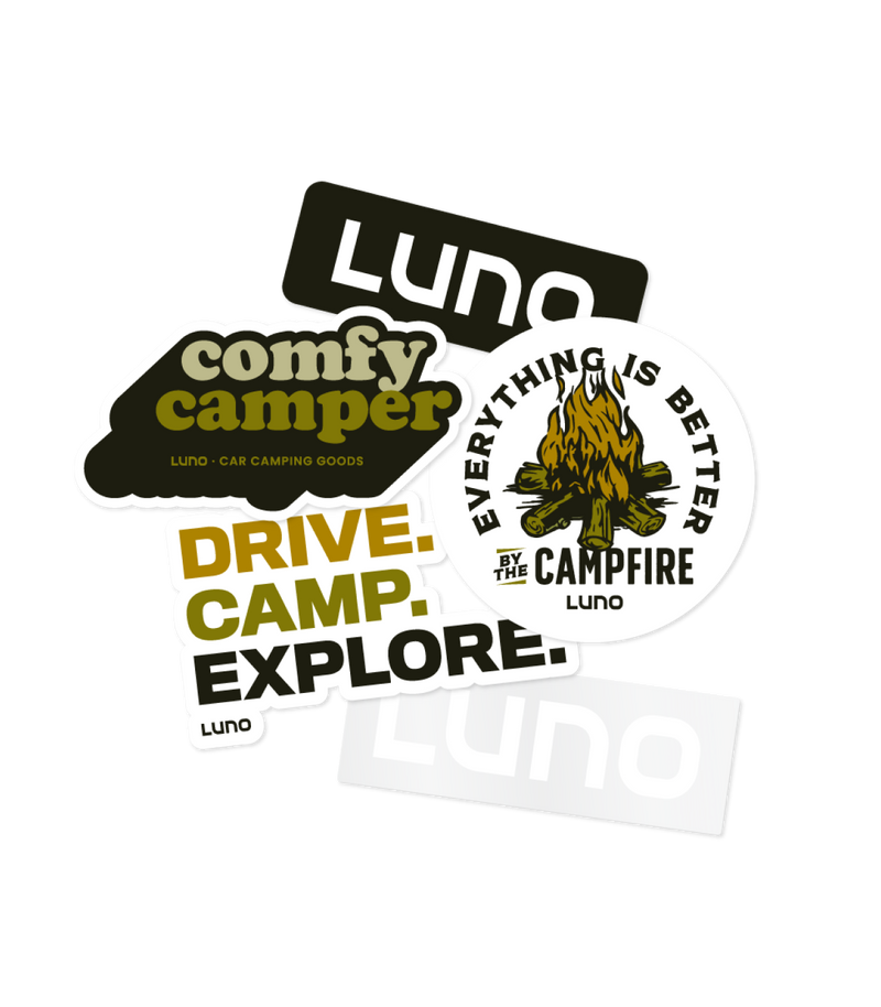 A collection of Luno-themed stickers including: "Luno" in black on white, "comfy camper" with accompanying text, "DRIVE. CAMP. EXPLORE," and "EVERYTHING IS BETTER BY THE CAMPFIRE" with a campfire illustration.