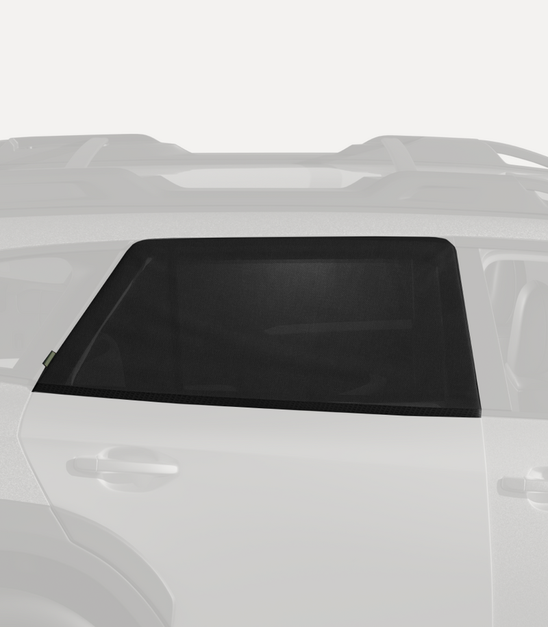 A partially visible vehicle with a side window shade installed on the rear side window. The shade is black, providing sun protection and privacy. The rest of the car is a light grey color, and the roof rack and part of the rear door are also visible.