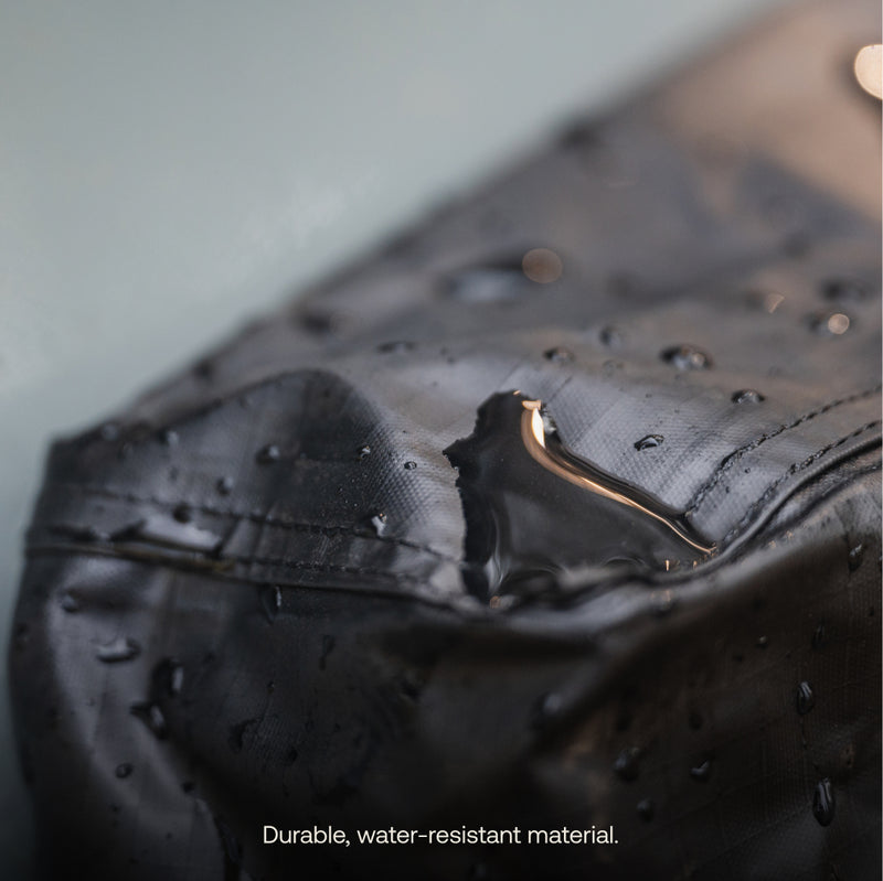 Close-up of water droplets beading on the surface of the Luno® Gear & Shoe Storage Bag, highlighting its durable, water-resistant material. Text at bottom: "Durable, water-resistant material.