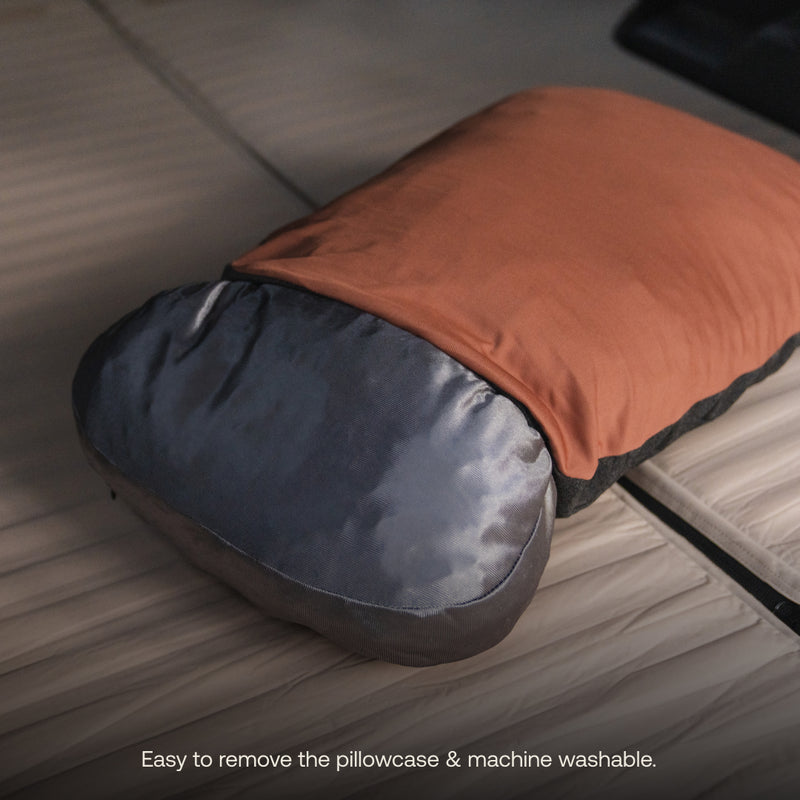 A Camping Pillowcase in orange and gray from Luno® rests on a bed. Made from cooling jersey knit, the case is easily removable and machine washable.