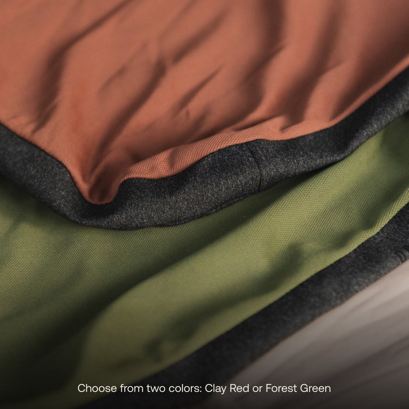 Close-up of the Luno® Camping Pillowcase, highlighting the two available colors: Clay Red and Forest Green. Crafted from a cooling jersey knit polyester blend fabric, each pillowcase is finished with dark edging. Text at the bottom reads, "Choose from two colors: Clay Red or Forest Green.