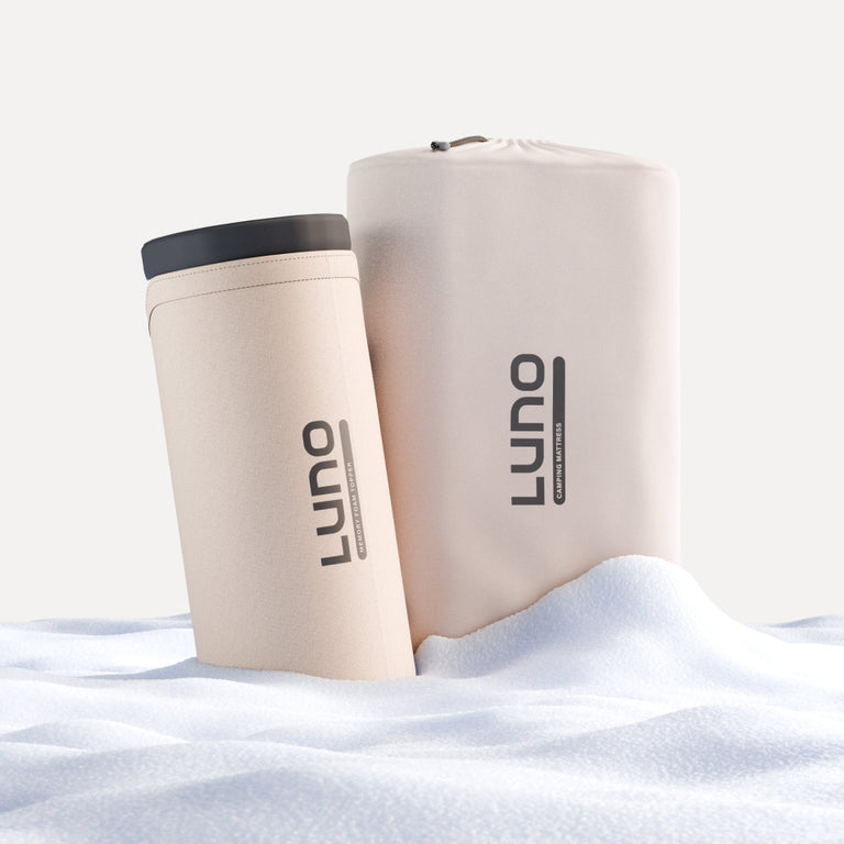 Two beige cylindrical items, one taller with a drawstring top and the other shorter with a black lid, rest on a soft, white surface. Both are branded with "Luno®," recognized for their Car Camping AIR Comfy Bundle.