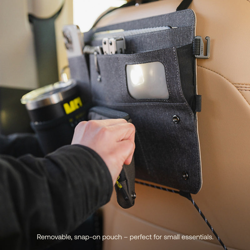 A person clips a small pouch onto a Luno HQ Seatback Organizer (Pre-Owned) on a car seat back, efficiently holding items like a phone and travel mug. Text says, "Removable, snap-on pouch – perfect for small essentials." Enjoy convenient USA shipping.