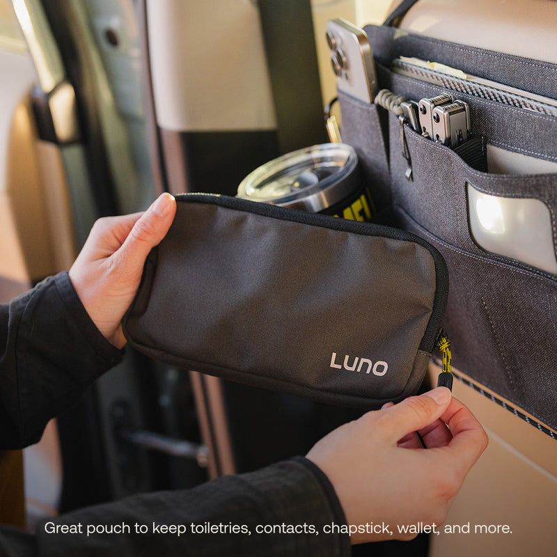 A Luno HQ Seatback Organizer, labeled "LUNO," fits snugly into a car door's compartment. Holding a small black pouch perfect for toiletries and chapstick, it also accommodates a phone and drink tumbler. Ideal for use with pre-owned gear. Text reads: "USA shipping available.