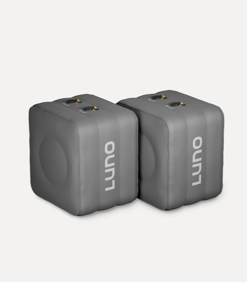 Two grey, rectangular inflatable camping pillows with the brand name "Luno" printed in white on the front are placed side by side against a plain background. The pillows feature round indents and dual valves for inflation and deflation.