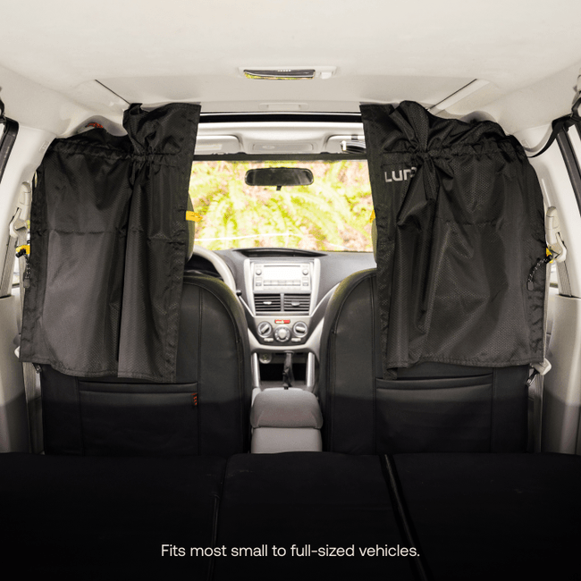 Interior view of a vehicle featuring black *Car Privacy Curtains (Pre-Owned)* by *Luno HQ* installed on the side windows. The image highlights the back seats and dashboard, emphasizing spaciousness and functionality. Text reads: "Fits most small to full-sized vehicles." Now available with quick USA shipping.
