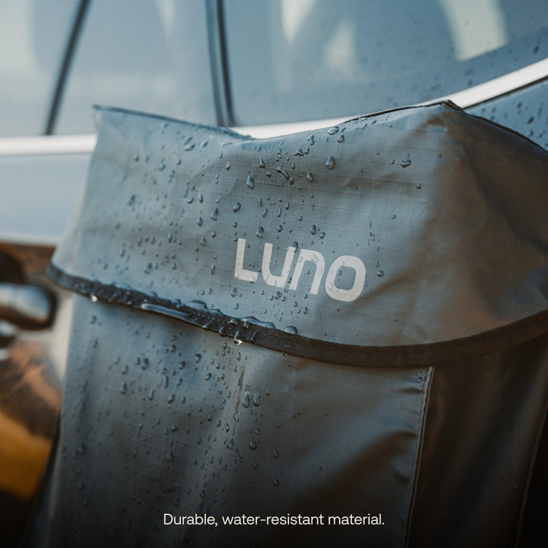 Close-up of a Gear & Shoe Storage Bag by Luno HQ on a car seat. Made from dark, water-resistant material with visible droplets, it safeguards pre-owned gear. Text below reads "Durable, water-resistant material.